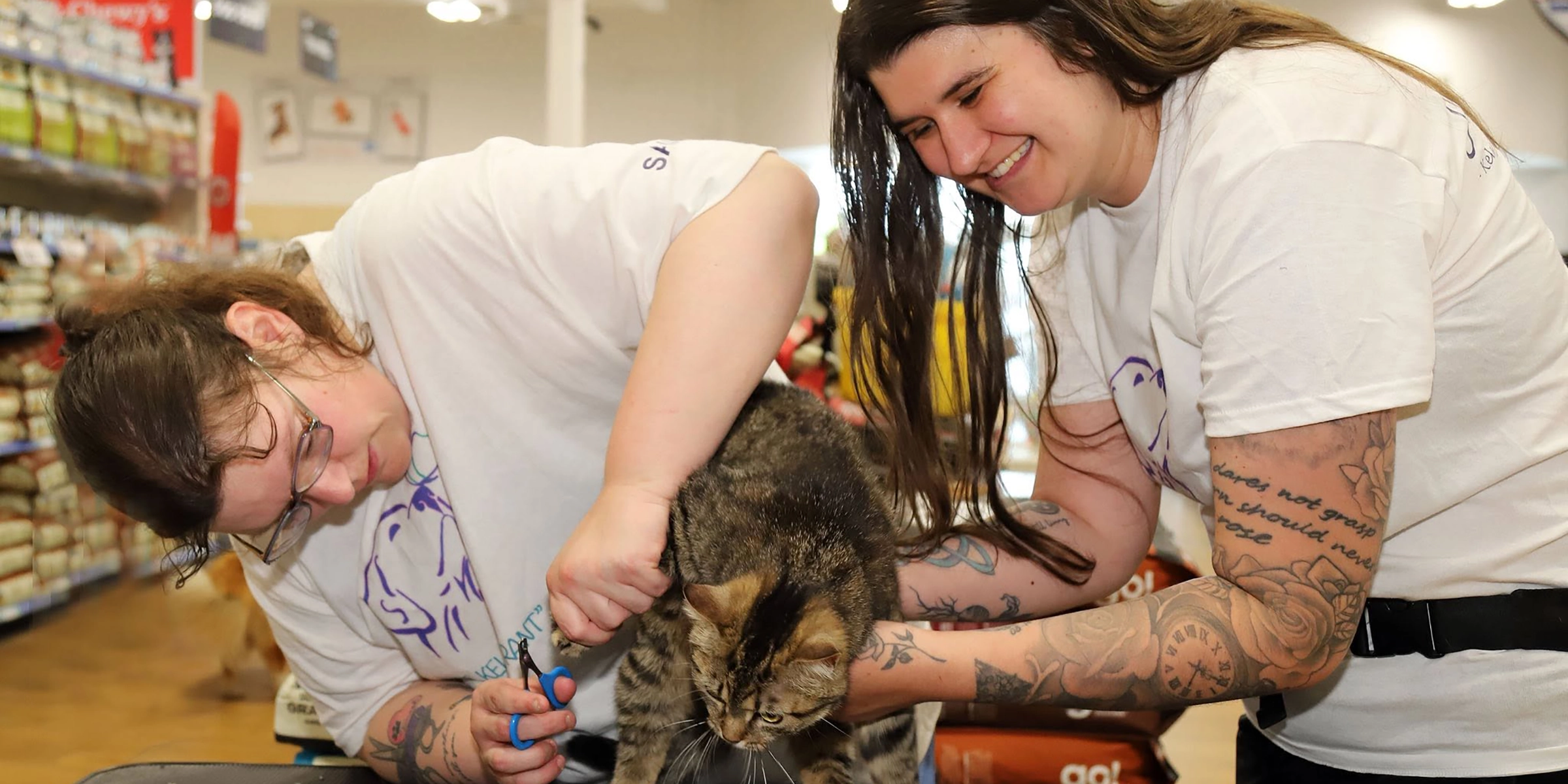 Sam and Alexis posing with a cat for a nail trim fundraiser